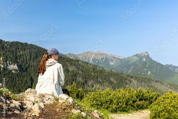 Fototapeta girl tourist sits on the edge of a cliff enjoying the view of the mountains and valley. travel and hiking in the mountains, Tatra Mountains, Poland