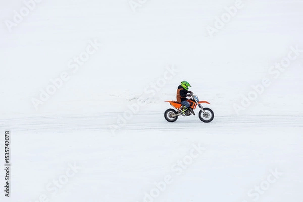 Obraz A man is riding a dirt bike on a snowy road