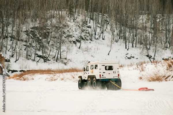 Obraz A white truck with a red hose attached to it is driving through a snowy field