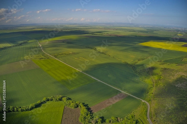 Fototapeta Winding roads through fields with sunrays, drone aerial view.