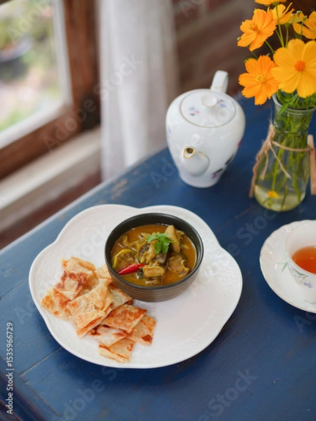 Fototapeta Thai food. Local Name is Kang Kiew Wan is Thai chicken vintage wooden, nearby is a pot of tea and teacup. Green Curry served with Roti flour by the window. Soft window light.
