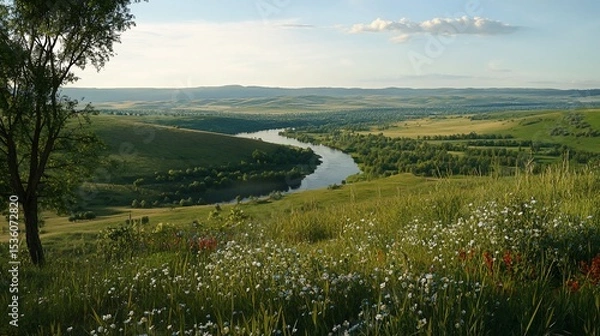 Fototapeta Green rolling hills and a meandering river under a soft sky with small clouds