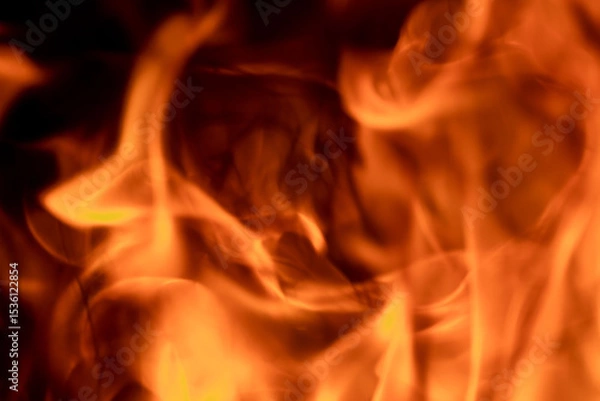 Fototapeta Close-up image of bright orange flames against a backdrop of black ash and burnt debris. A strong visual composition depicting the power, energy, and beauty of nature in the form of the fire element. 