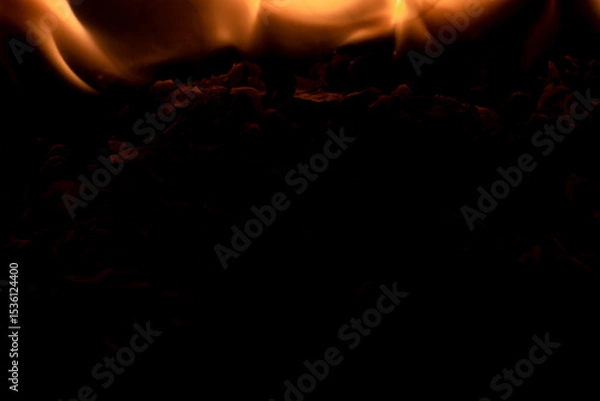 Fototapeta Close-up image of bright orange flames against a backdrop of black ash and burnt debris. A strong visual composition depicting the power, energy, and beauty of nature in the form of the fire element. 