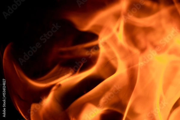 Fototapeta Close-up image of bright orange flames against a backdrop of black ash and burnt debris. A strong visual composition depicting the power, energy, and beauty of nature in the form of the fire element. 