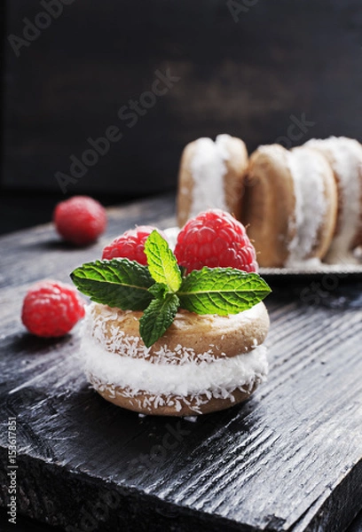 Fototapeta Homemade ice cream sandwiches  with coconut flakes raspberries and mint on old black wooden board, over marble texture background. Top view with copy space.