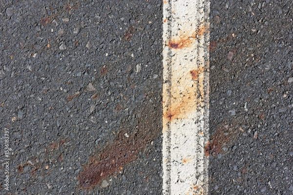 Fototapeta Asphalt road with a white painted line and rust stains close-up abstract textured background