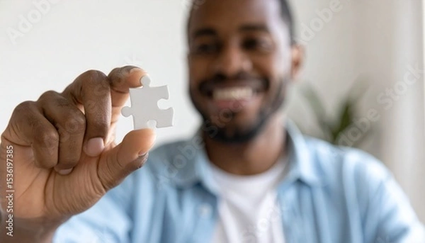 Fototapeta Smiling African American Man Holding Up a Single Puzzle Piece Showing Connection and Success in Business Strategy Problem Solving and Solutions for Teamwork
