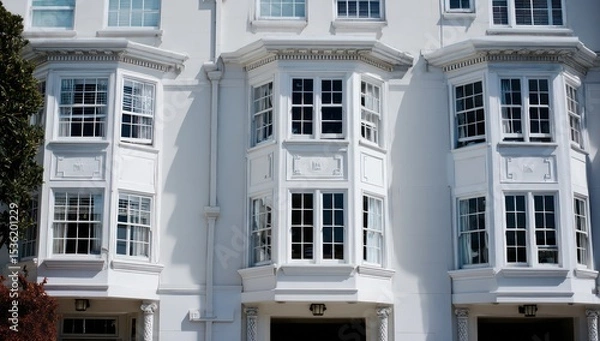 Fototapeta Bay windows arranged elegantly on a white building facade, contributing to its architectural grace.