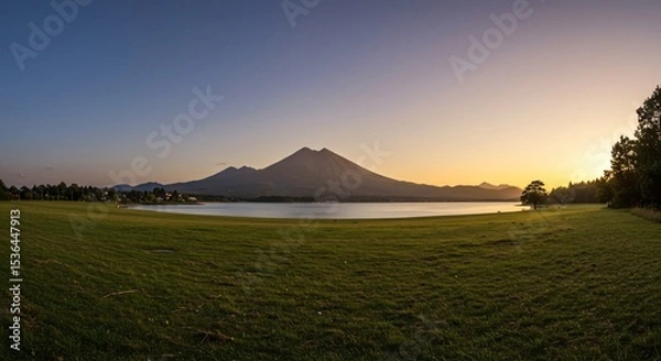 Fototapeta a grassy field with a lake and mountains in the background
