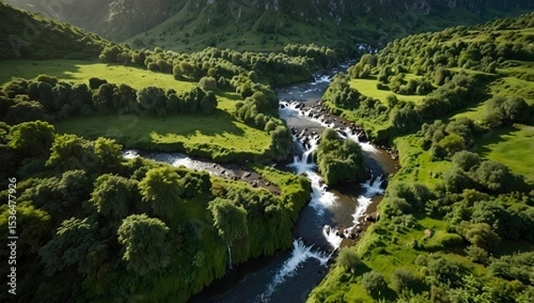 Obraz Aerial view of a lush green mountainous valley with winding river, sunlight casting shadows over dense forest trees, showcasing untouched natural beauty and serene atmosphere