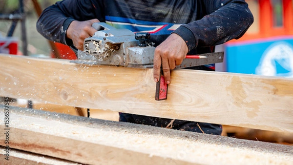Fototapeta Male carpenter hand using angle ruler for wood squaring and planing on wooden plank by electric planer on workbench in workshop. Wood measuring and shaving process for lumber industry