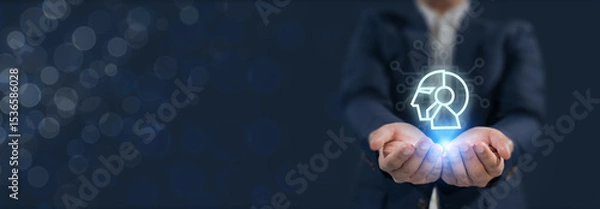 Obraz Human-AI collaboration concept. Businessman holds a glowing digital icon of a human-AI hybrid head, synergy between human intelligence and artificial intelligence  in modern technology and innovation.