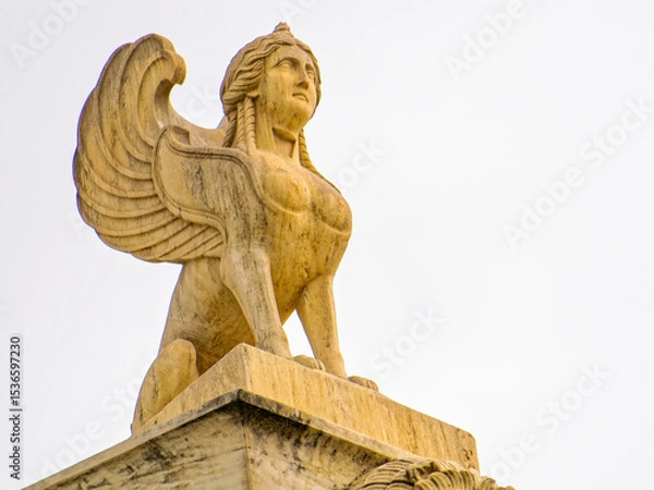 Obraz Sphinx sculpture, an ancient Greek mythical creature with the head of a woman, the body of a lion, and eagle wings, symbolizing wisdom and mystery. Space for text and logo.