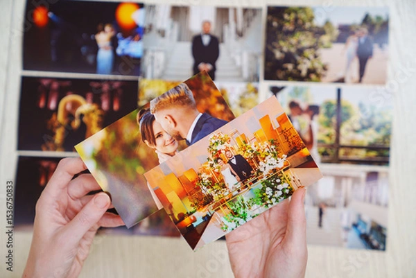 Obraz hands with photos and Printed wedding photos laid out on a wooden surface.