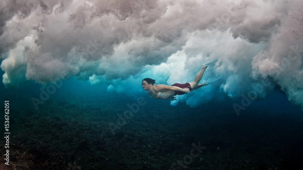 Obraz Man dives and swims underwater under the breaking wave