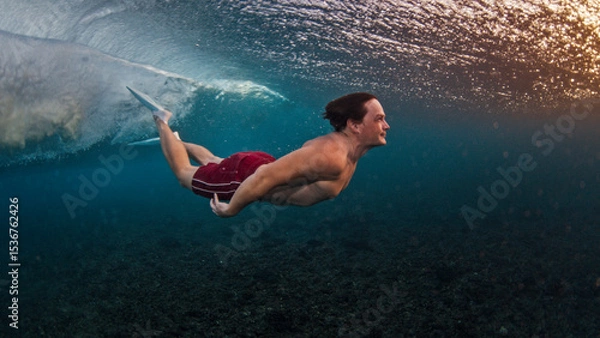 Obraz Man dives and swims underwater under the breaking wave