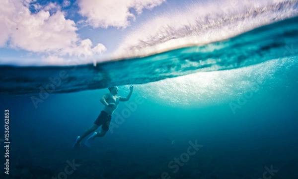 Obraz Man swims in the sea with breaking waves. Splitted shot of the male swimming in the ocean on a surfing spot