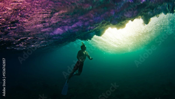 Obraz Man dives and swims underwater under the breaking wave