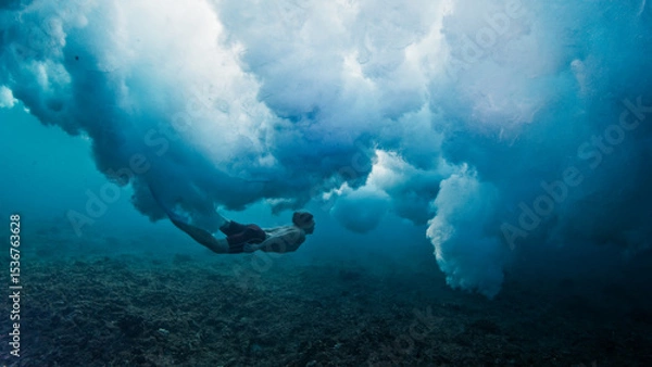 Obraz Man dives and swims underwater under the breaking wave