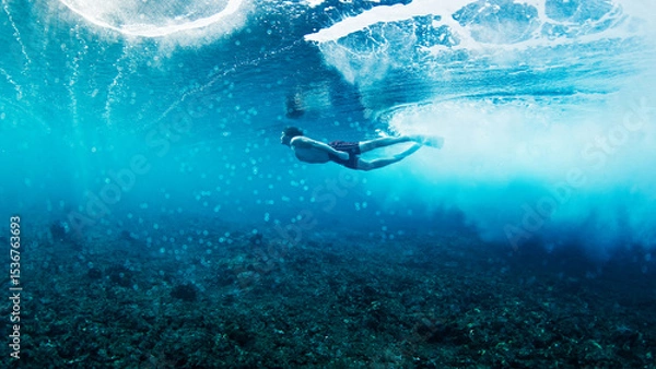 Obraz Man dives and swims underwater under the breaking wave
