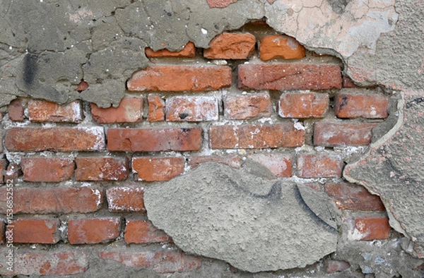 Fototapeta Wall with visible brick damage and rough texture in an outdoor setting during daylight
