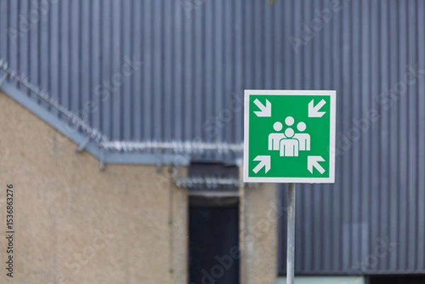 Obraz A vivid green emergency assembly point sign, clearly indicating a designated safe gathering area.