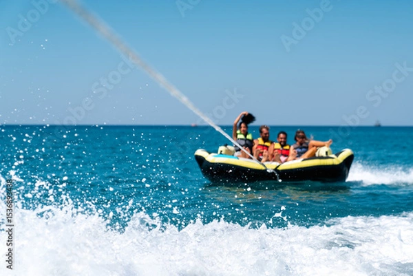 Fototapeta A group of friend having fun behind a speedboad on the sea