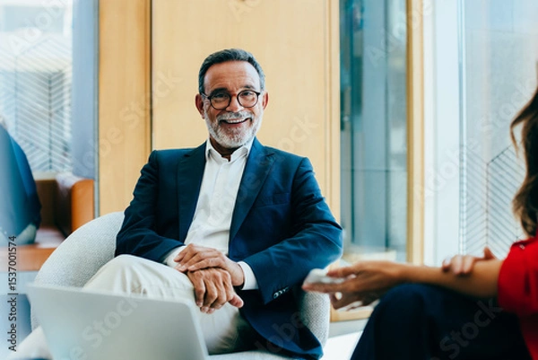 Fototapeta Senior businessman smiling during a meeting in a modern office setting