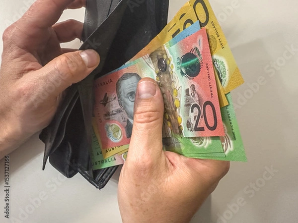 Fototapeta close up man hand holds wallet with AUD Australian dollar paper money on white isolated background