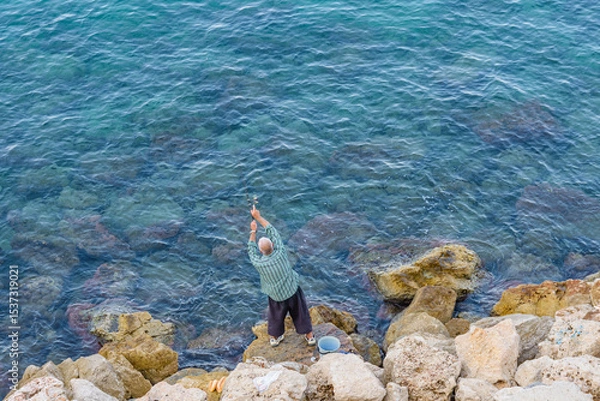 Fototapeta Fisherman catching fish at the beach at seaside