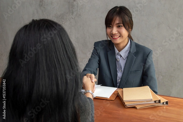 Obraz A professional business meeting between two women discussing opportunities and shaking hands with smiles.