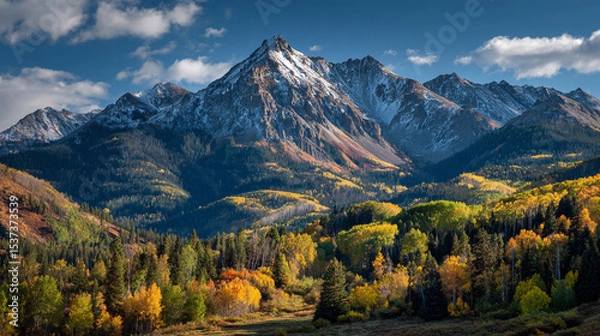Obraz A scenic view of snow capped mountains with autumn foliage and a cloudy blue sky in the background