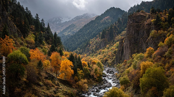 Obraz A view of a river flowing through a mountain valley with trees in autumn colors and cloudy sky above