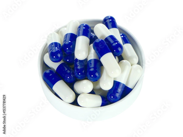Fototapeta Bulk blue and white capsule pills on a white tray isolated on white background.