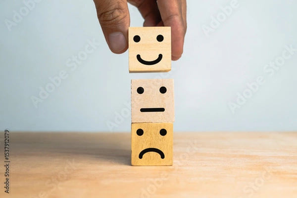 Fototapeta male hand stack sad, flat and happy face expression emoticon on wooden cubes on wooden table