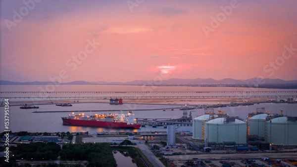 Obraz Aerial view of an LNG tanker docked at an offshore terminal with multiple pipelines, storage tanks, and an industrial complex. Captures global energy logistics