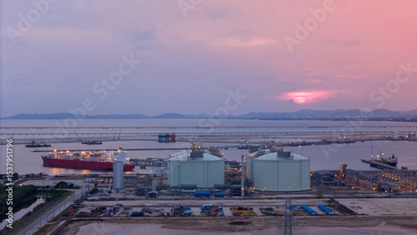 Obraz Aerial view of an LNG tanker docked at an offshore terminal with multiple pipelines, storage tanks, and an industrial complex. Captures global energy logistics