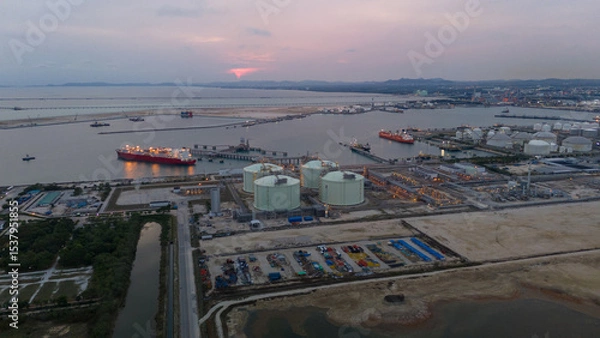 Obraz Aerial view of an LNG tanker docked at an offshore terminal with multiple pipelines, storage tanks, and an industrial complex. Captures global energy logistics