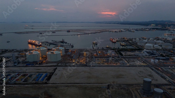 Obraz Aerial view of an LNG tanker docked at an offshore terminal with multiple pipelines, storage tanks, and an industrial complex. Captures global energy logistics