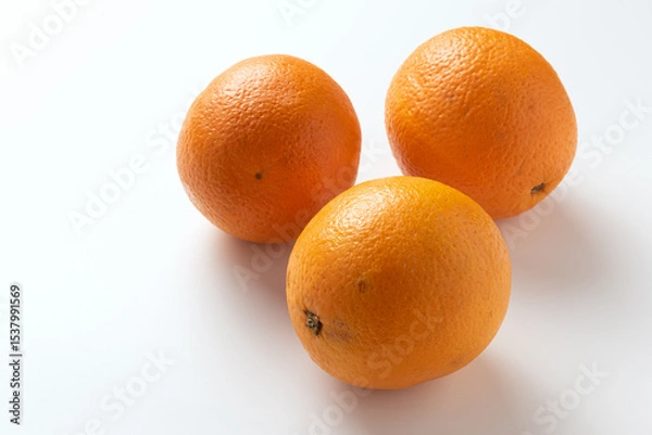 Fototapeta Three ripe oranges close-up ionized on white background.