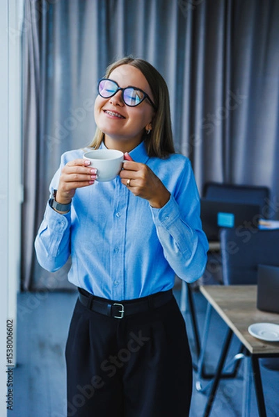 Fototapeta A Joyful Businesswoman is taking a delightful coffee break while enjoying a moment of relaxation in a modern office setting, embodying professionalism and enthusiasm amid her busy work life
