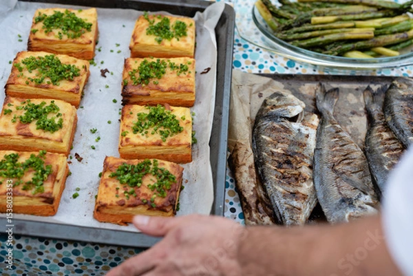 Fototapeta Grilled fish with vegetables. Gratin made from potatoes and asparagus ready to eat. Chef preparing main dinner on plate. Healthy food from grill as a delicious meal. Close up.