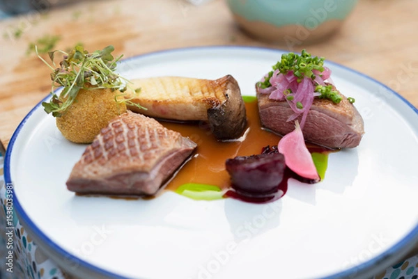Fototapeta Gourmet food. A piece of grilled meat with mushroom and sauce on white plate in restaurant. Fresh served duck on main dish. Close up.