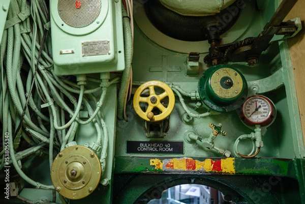 Obraz A detailed view of submarine machinery shows yellow and green control valves, a pressure gauge, and thick cables. The control panel is marked as Bulkhead 40 inside the submarine.