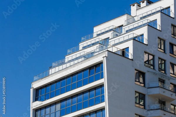 Obraz City view on a sunny day. Modern building and houses against the blue sky.