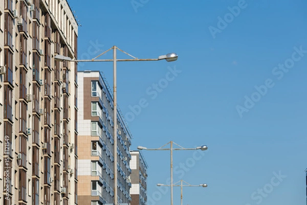 Obraz City view on a sunny day. Modern building and houses against the blue sky.