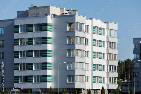 Obraz City view on a sunny day. Modern building and houses against the blue sky.
