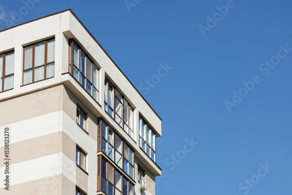 Obraz City view on a sunny day. Modern building and houses against the blue sky.