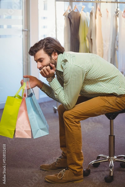 Obraz Pastel shopping bags resting on rolling stool in retail showroom, with frosted glass partition
